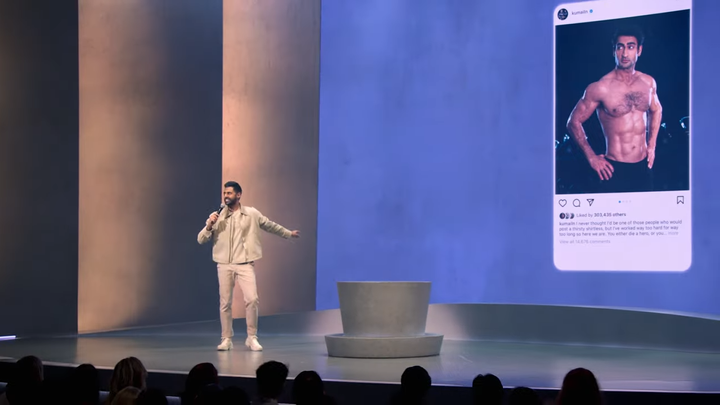 Hasah Minhaj performing on a stage with an image of Kumail Nanjiani's Instagram account projected behind him.